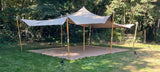 Stretchtent met gelakte eucalyptus palen in een tuin